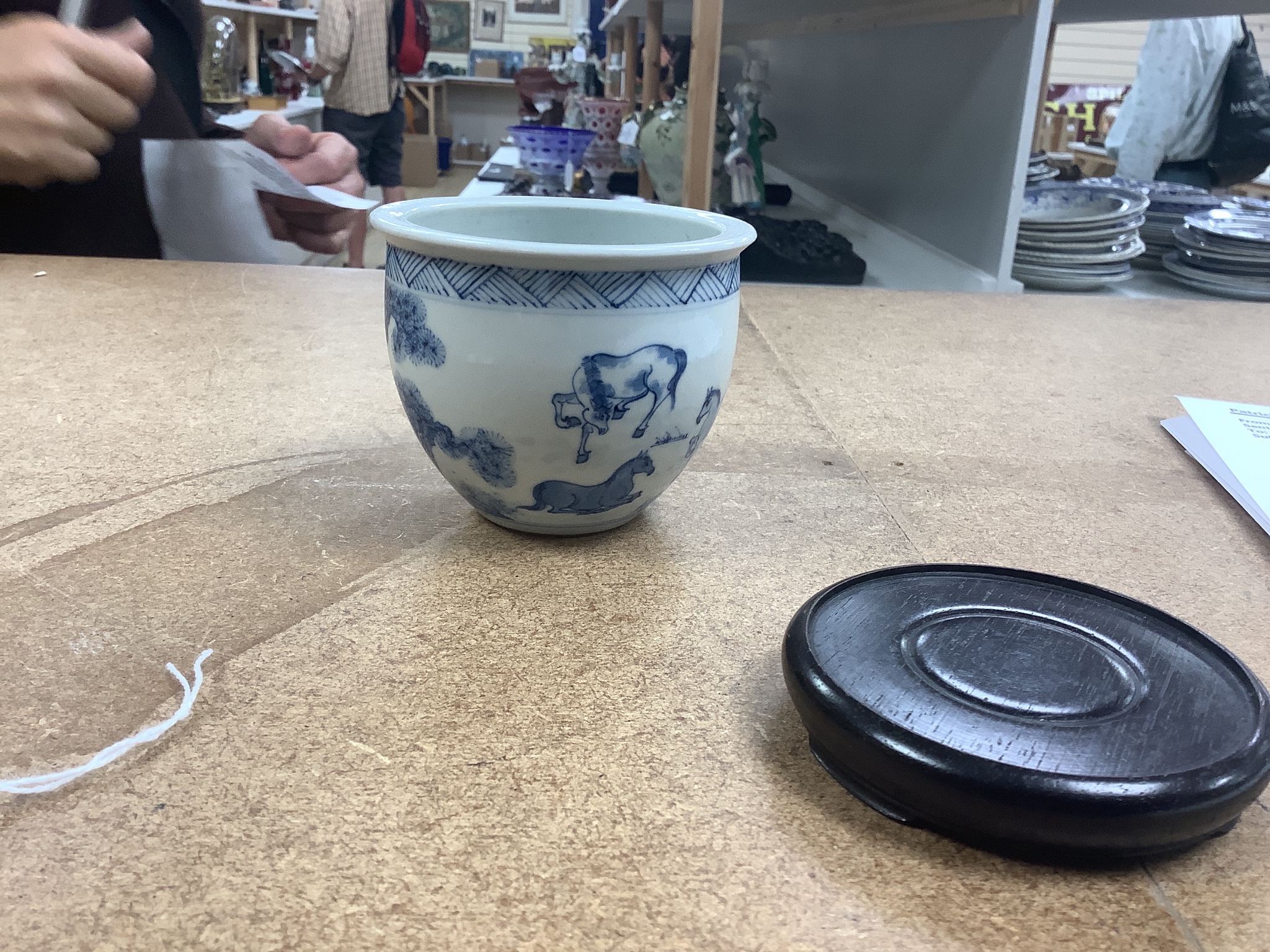 A Chinese blue and white ‘eight horses’ brush pot, on wooden stand, 8cm tall including stand